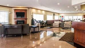 A spacious hotel lobby with a fireplace, seating area, and a reception desk. - Comfort Suites Canton - Detroit (Canton)