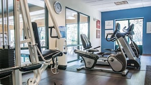 A gym with cardio machines, weight benches, and a wall clock. - Comfort Suites Canton - Detroit (Canton)