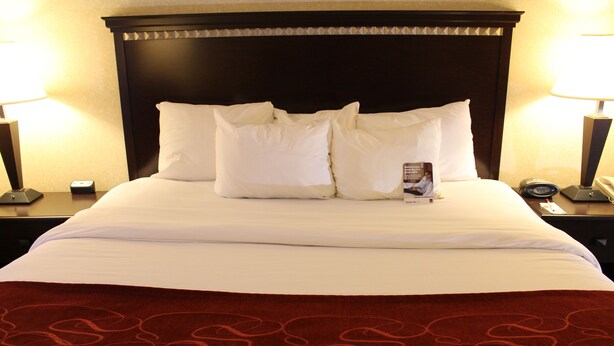 A neatly made bed with white linens and a red patterned throw blanket. - Comfort Suites Canton - Detroit (Canton)