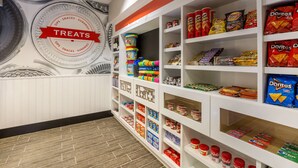 A snack aisle with shelves stocked with various treats like Doritos, Lay's, and Pringles. - Hampton Inn & Suites San Diego-Poway (Poway)