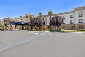 A hotel entrance with clear signage, a parking lot with marked handicapped spaces, and a building with multiple windows and a flat roof. - Hampton Inn & Suites Lancaster (Lancaster)