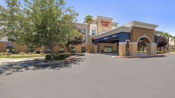 A Hampton Inn & Suites by Hilton with a clear entrance, a parking lot, and a sign indicating a handicap parking area.