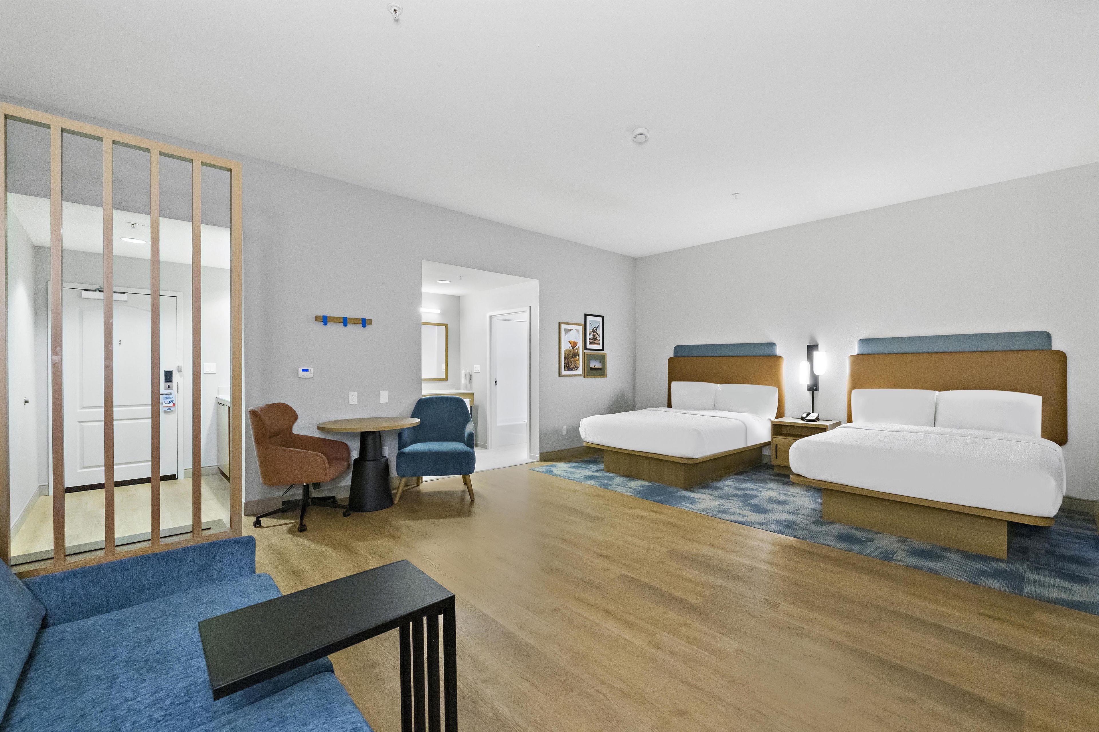 Una habitación de hotel con dos camas, un escritorio, una silla y una mesita.