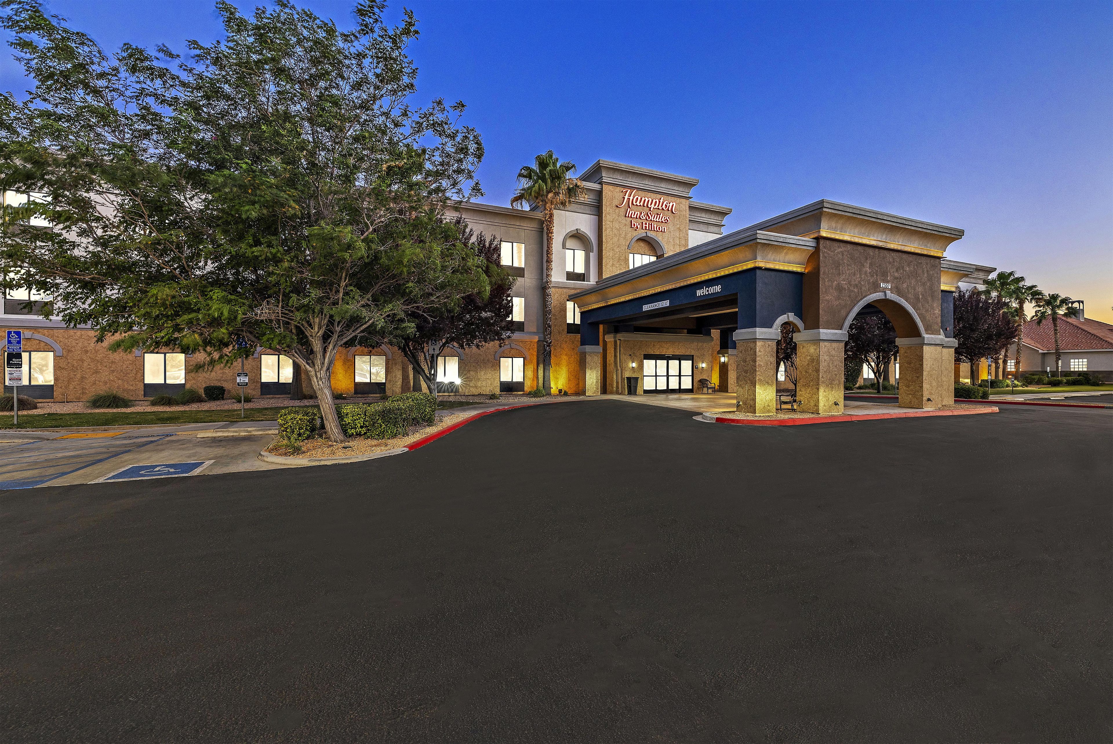 A hotel entrance with a clear driveway, a parking sign, and a sign indicating guest parking.