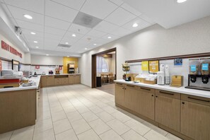 A clean, well-lit breakfast area with a counter, coffee machines, and a sign for 'Happy Breakfast Here'.