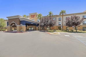 A Hampton Inn & Suites by Hilton hotel with a clear sky, parking lot, and a covered entrance. - Hampton Inn & Suites Lancaster (Lancaster)
