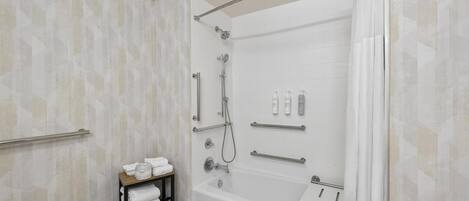 Un baño moderno con ducha a ras de suelo, bañera y repisa con toallas.