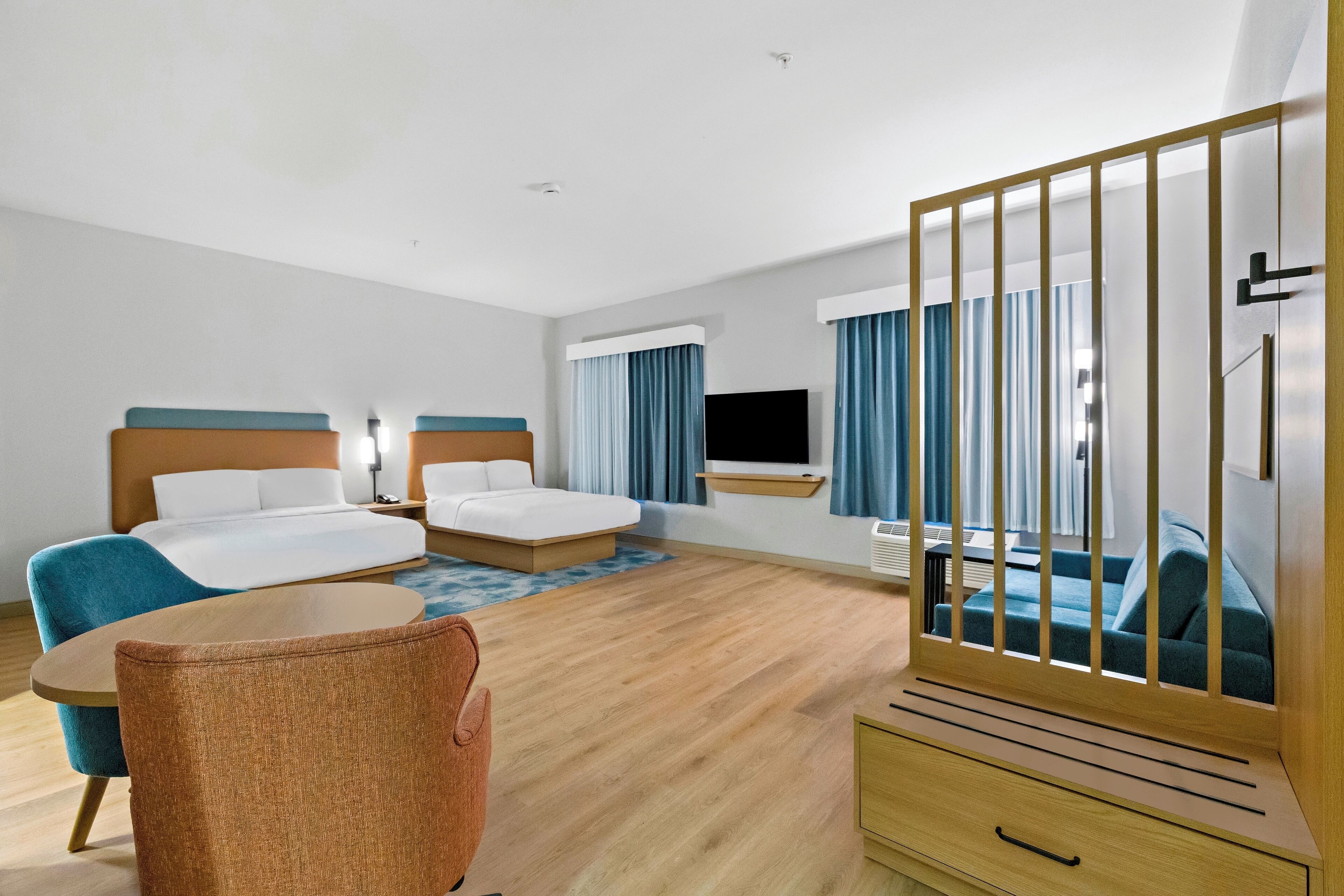 A hotel room with two beds, a TV, a desk, and a chair.