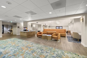 A spacious hotel lobby with a central seating area, a kitchenette, and a patterned carpet. - Hampton Inn & Suites Lancaster (Lancaster)