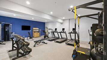 Une salle de sport équipée de tapis de course, d’appareils de musculation et d’un support pour les exercices de squat.