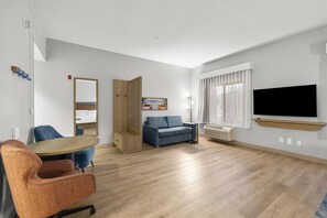 A modern living room with a sofa, a coffee table, and a TV mounted on the wall. - Hampton Inn & Suites Lancaster (Lancaster)