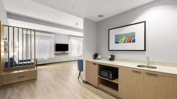 A modern kitchen with a microwave, sink, and a framed artwork on the wall.
