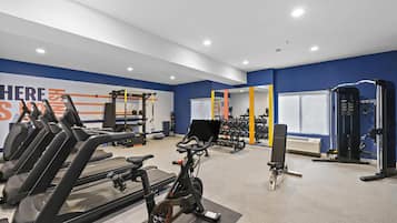 Un gimnasio con equipo de ejercicio, incluyendo cintas de correr y máquinas de pesas.