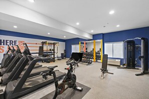 Un gimnasio con equipo de ejercicio, incluyendo cintas de correr y máquinas de pesas.