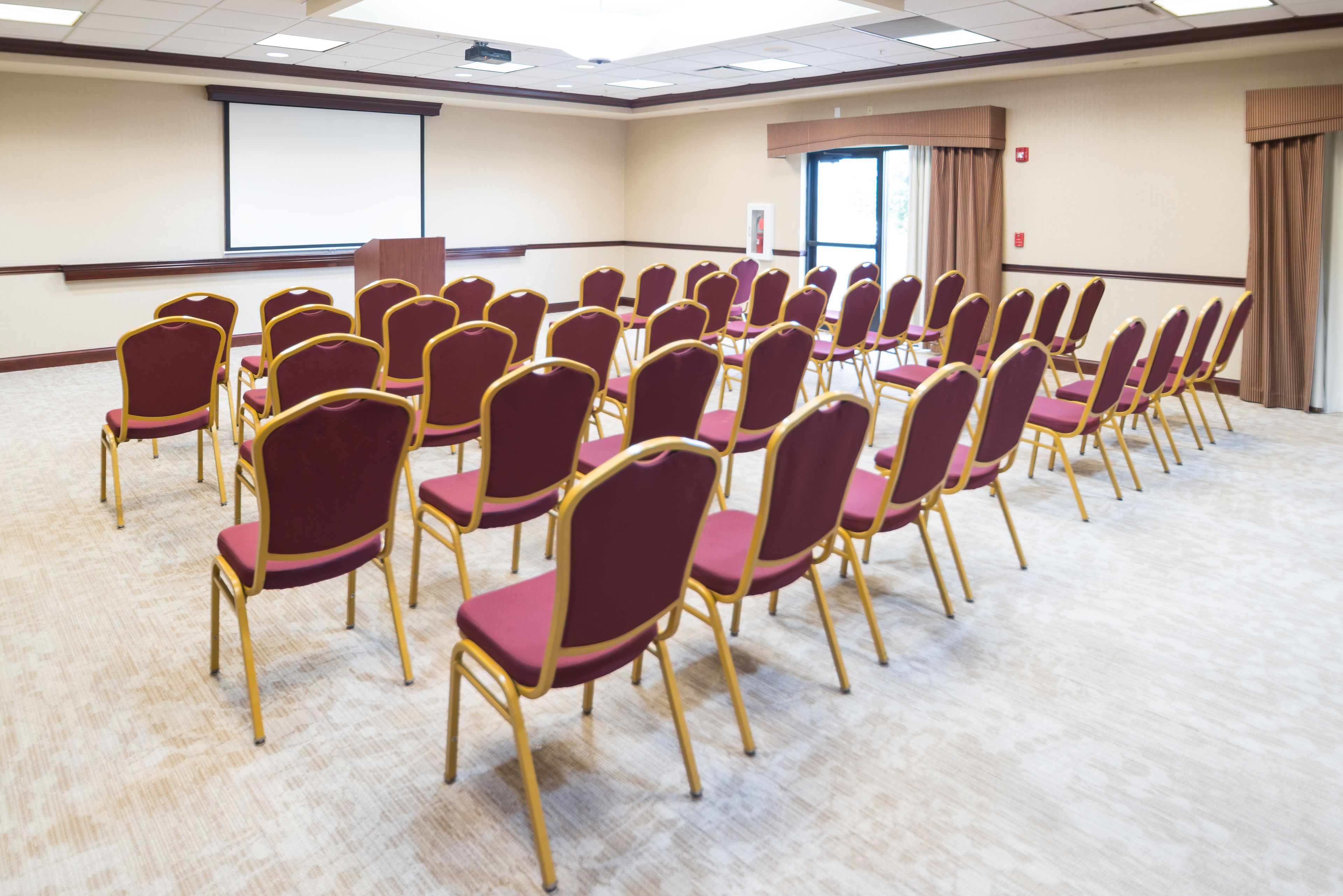 Ein Konferenzraum mit Reihen von Stühlen und einer Projektionsleinwand.
