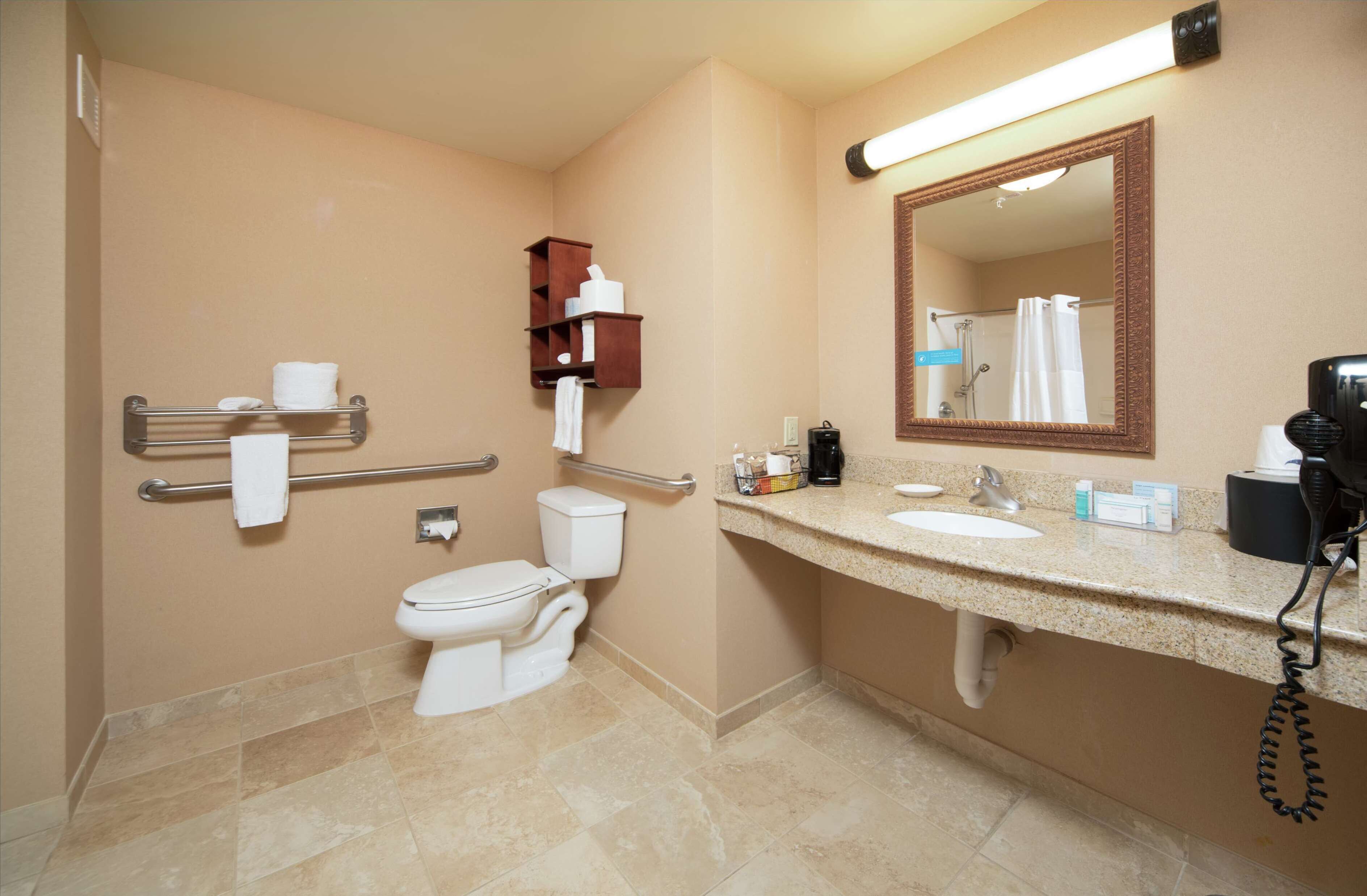 A bathroom with a toilet, sink, mirror, towel rack, and a telephone.