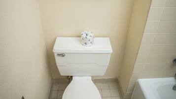A small bathroom with a toilet, two towels hanging on a rack, and a toilet paper holder.