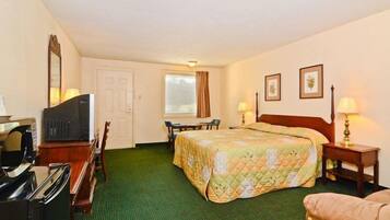 A hotel room with a bed, a desk, a chair, a television, and a window.