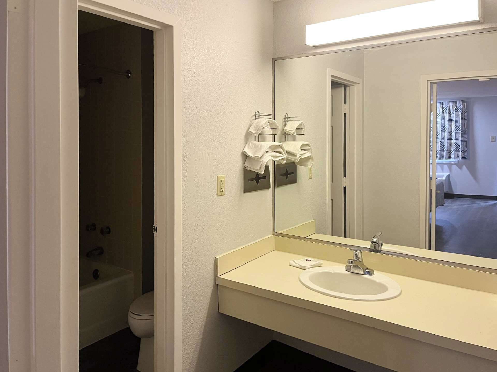 A bathroom with a white sink, mirror, and towel rack.