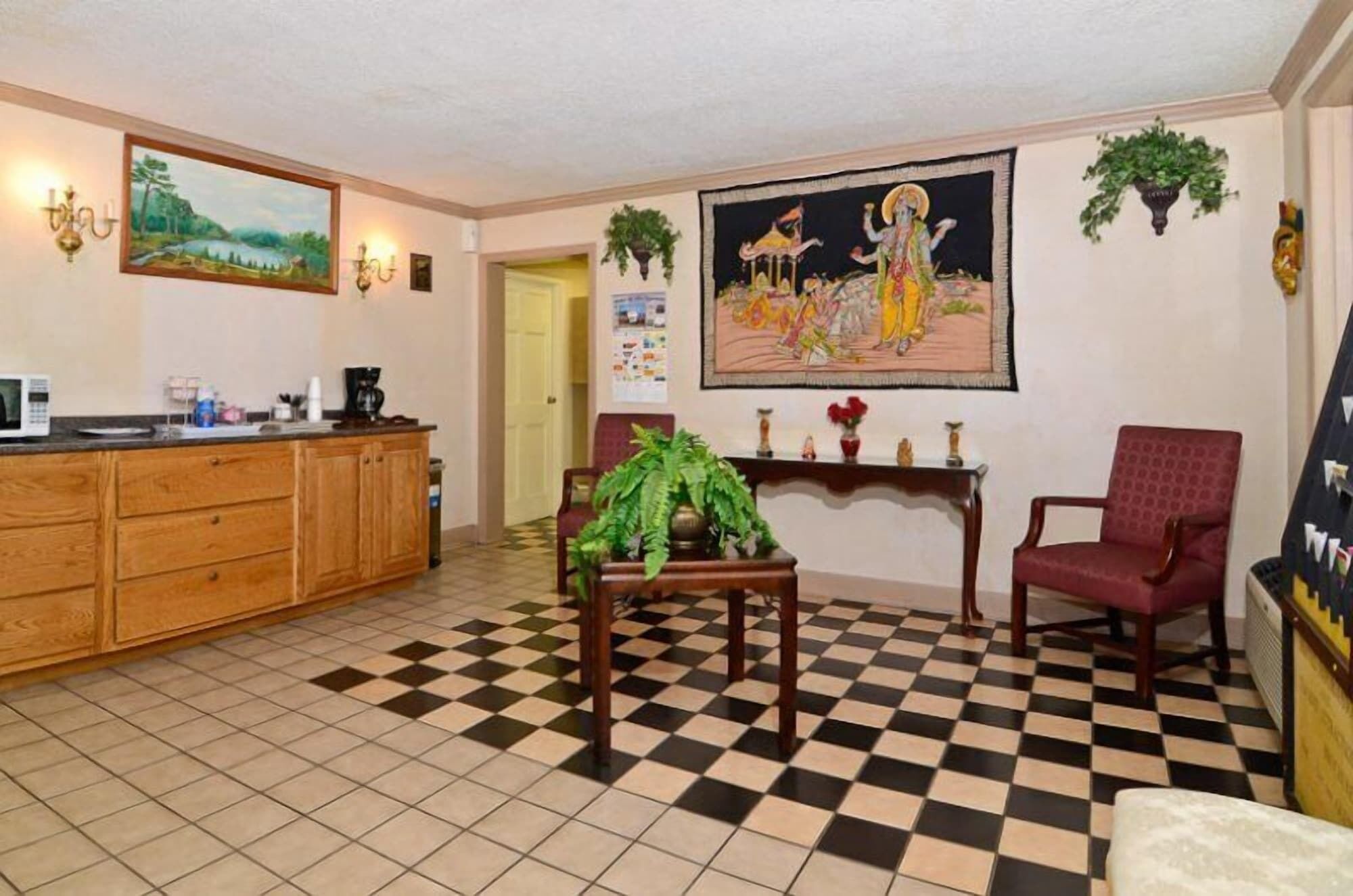 A spacious living area with a checkered floor, wooden furniture, and artwork on the walls.
