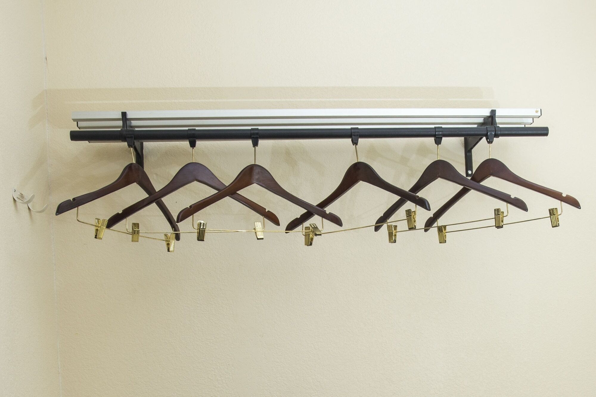Un porte-manteau mural doté de cinq cintres en bois et de pinces en laiton.