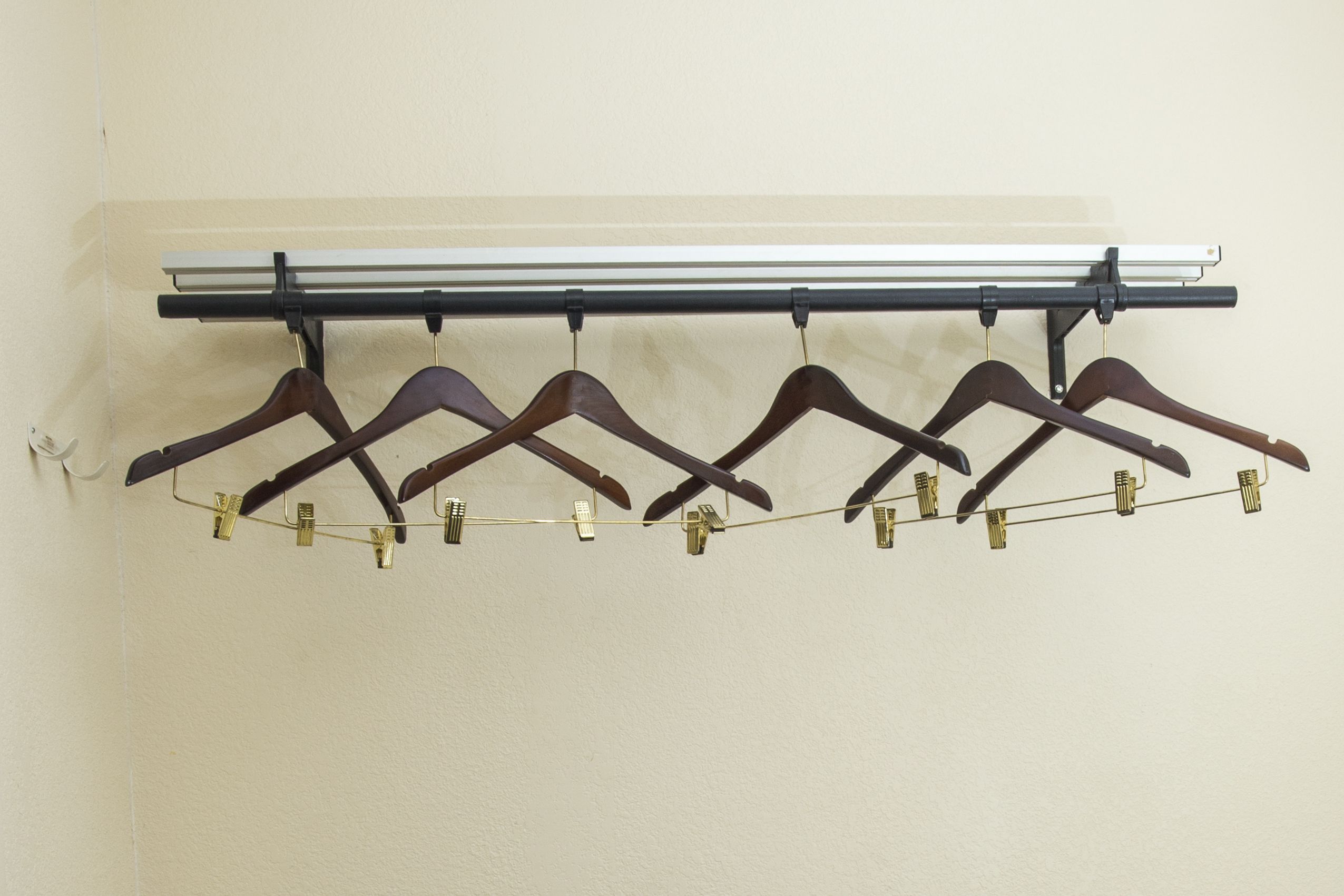 A wall-mounted coat rack with multiple wooden hangers and a metal rod.