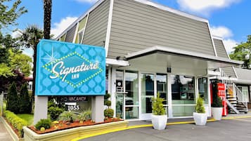 A Signature Inn building with a blue sign, glass entrance, and a Coca-Cola vending machine.