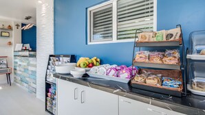 A kitchen area with a blue wall, a window with blinds, a fruit bowl, a bread rack, and a refrigerator. - Signature Inn Eugene (Eugene)