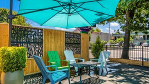 An outdoor patio with a table, chairs, and a large umbrella. - Signature Inn Eugene (Eugene)