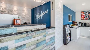 A modern reception area with a blue accent wall, a decorative counter, and a coffee station. - Signature Inn Eugene (Eugene)