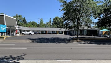A motel with a row of rooms, a parking lot, and a small outdoor area with a tent.