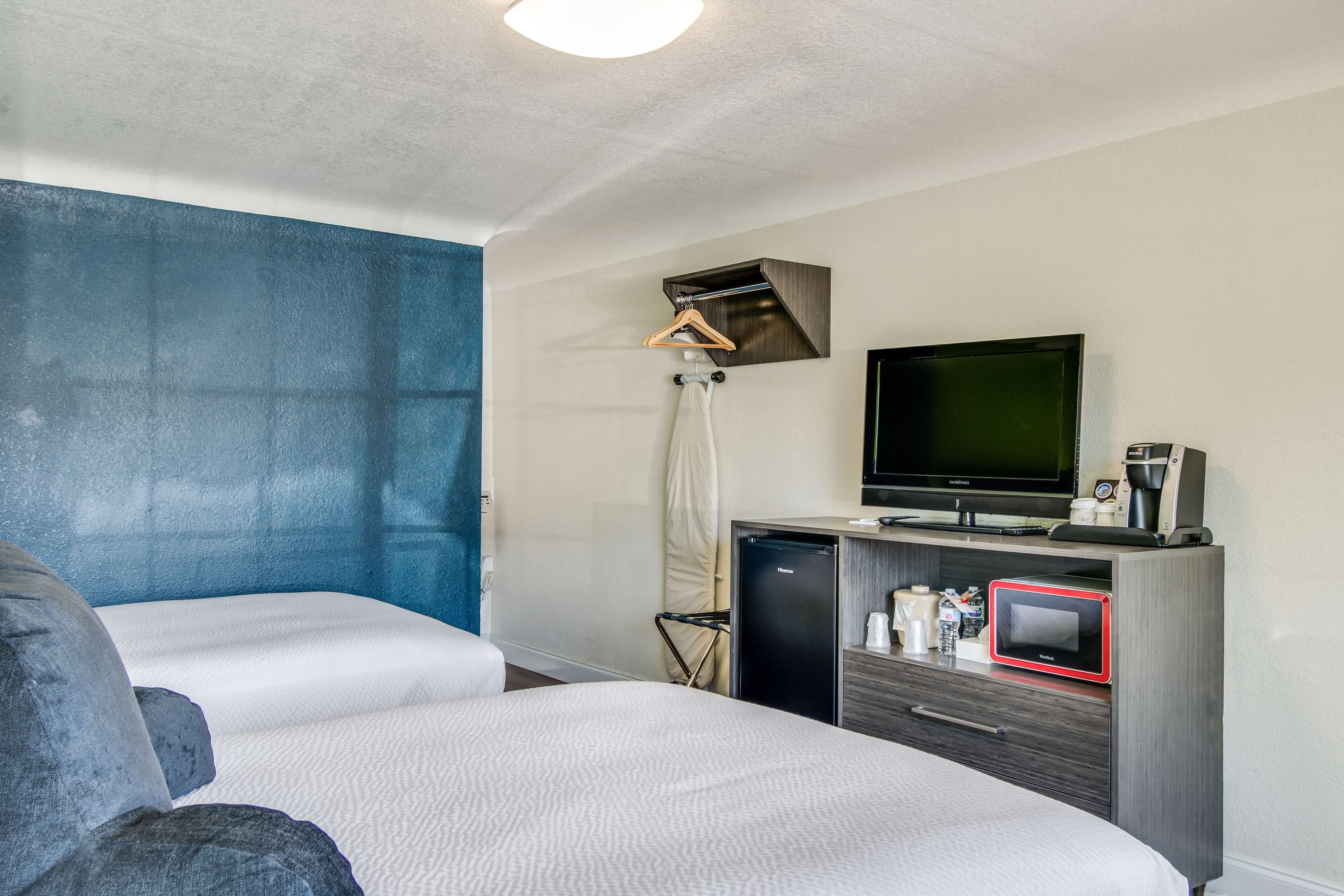 Een hotelkamer met twee bedden, een televisie, een minibar en een klein bureau.