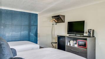 Een hotelkamer met twee bedden, een televisie, een minibar en een klein bureau.