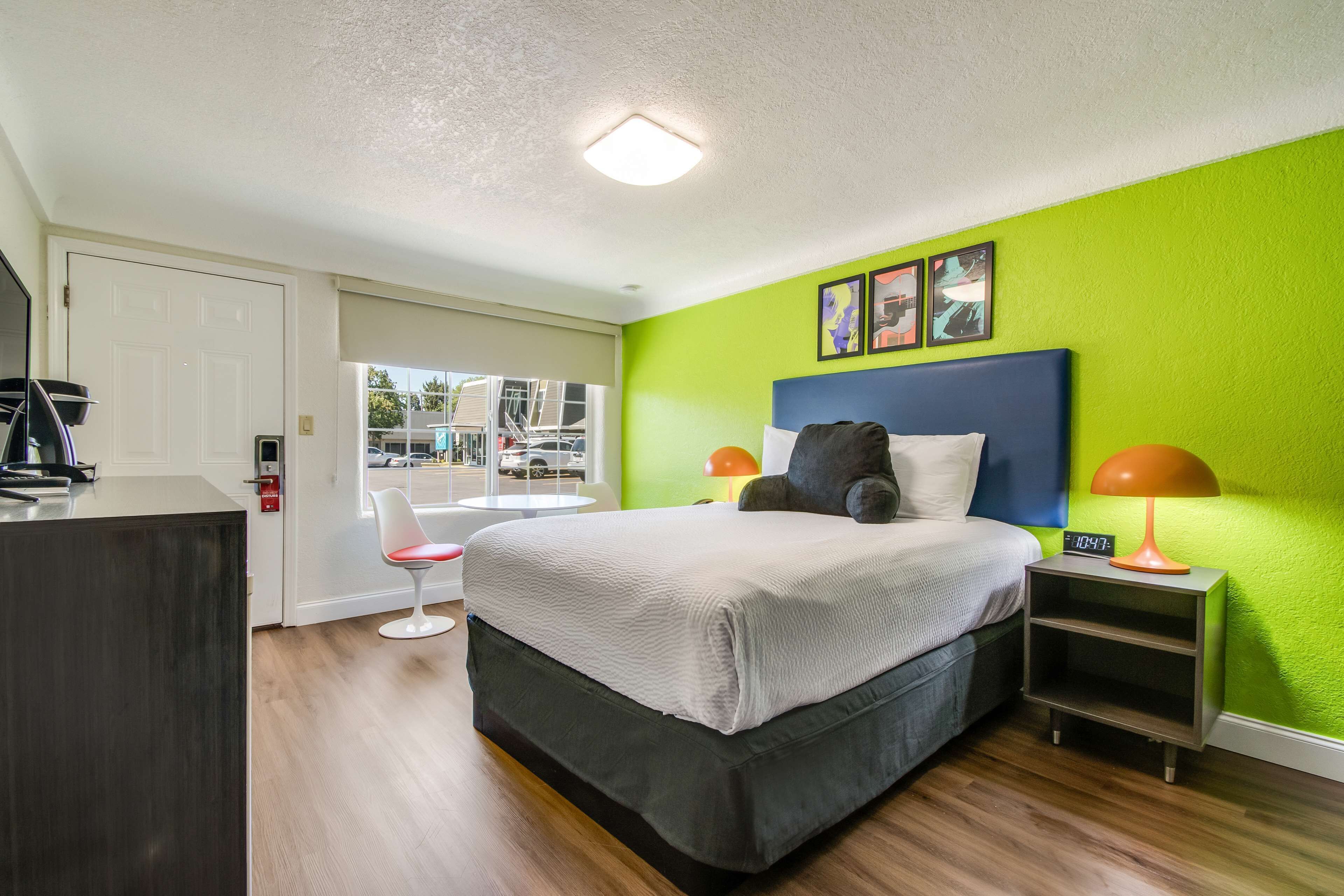 A modern hotel room with a large bed, a desk, and a chair.