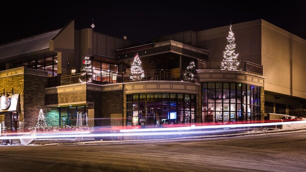 A modern building with a curved facade, large windows, and multiple balconies. - High Peaks Resort (Lake Placid)