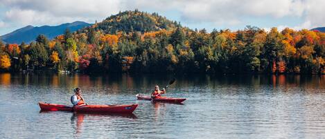 Two kayaks on a calm lake with a forested mountain in the background.