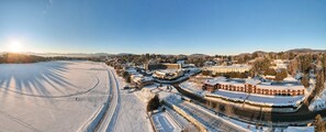 A snow-covered landscape with a large building complex, including a hotel with multiple floors and a parking area. - High Peaks Resort (Lake Placid)