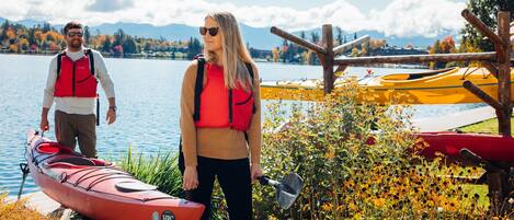 A lakeside scene with a red kayak, a yellow kayak, and a wooden dock.