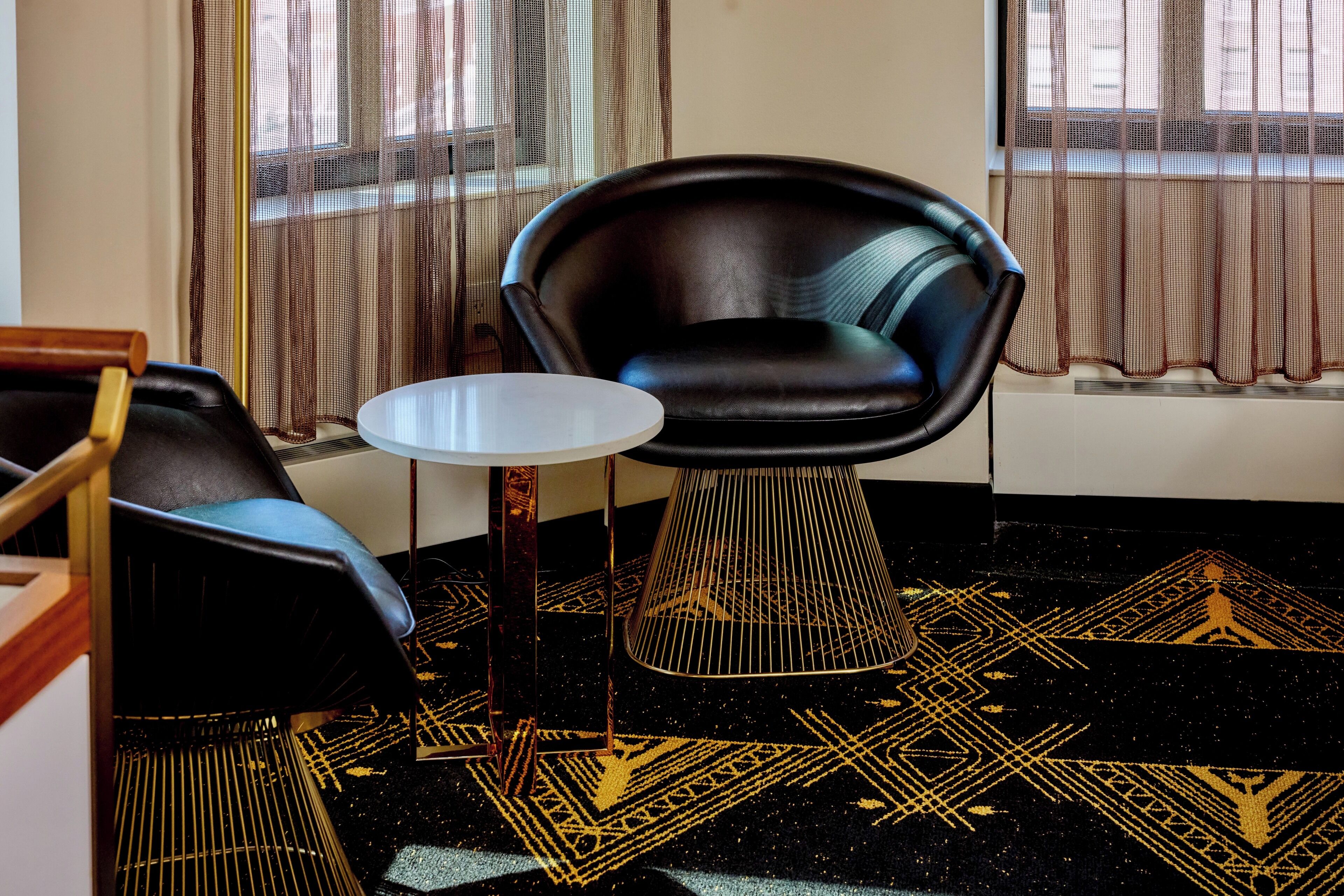 A room with a black leather chair, a small round table, and a patterned carpet.