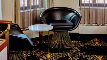 A room with a black leather chair, a small round table, and a patterned carpet.
