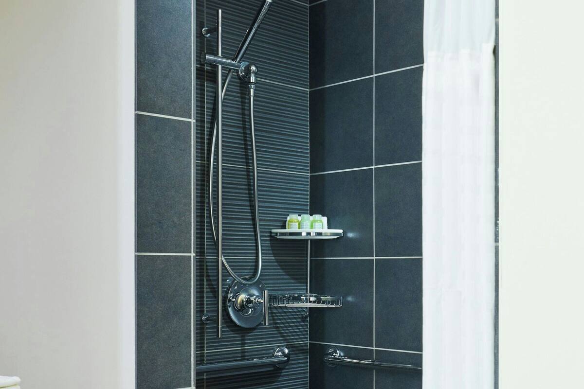 Une douche moderne avec une porte en verre, un porte-serviettes et une étagère pour les articles de toilette.