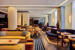 Un moderno vestíbulo de hotel con zonas de estar, chimenea y mostrador de recepción.