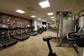 Une salle de sport équipée de tapis de course, de vélos elliptiques et de matériel de musculation.