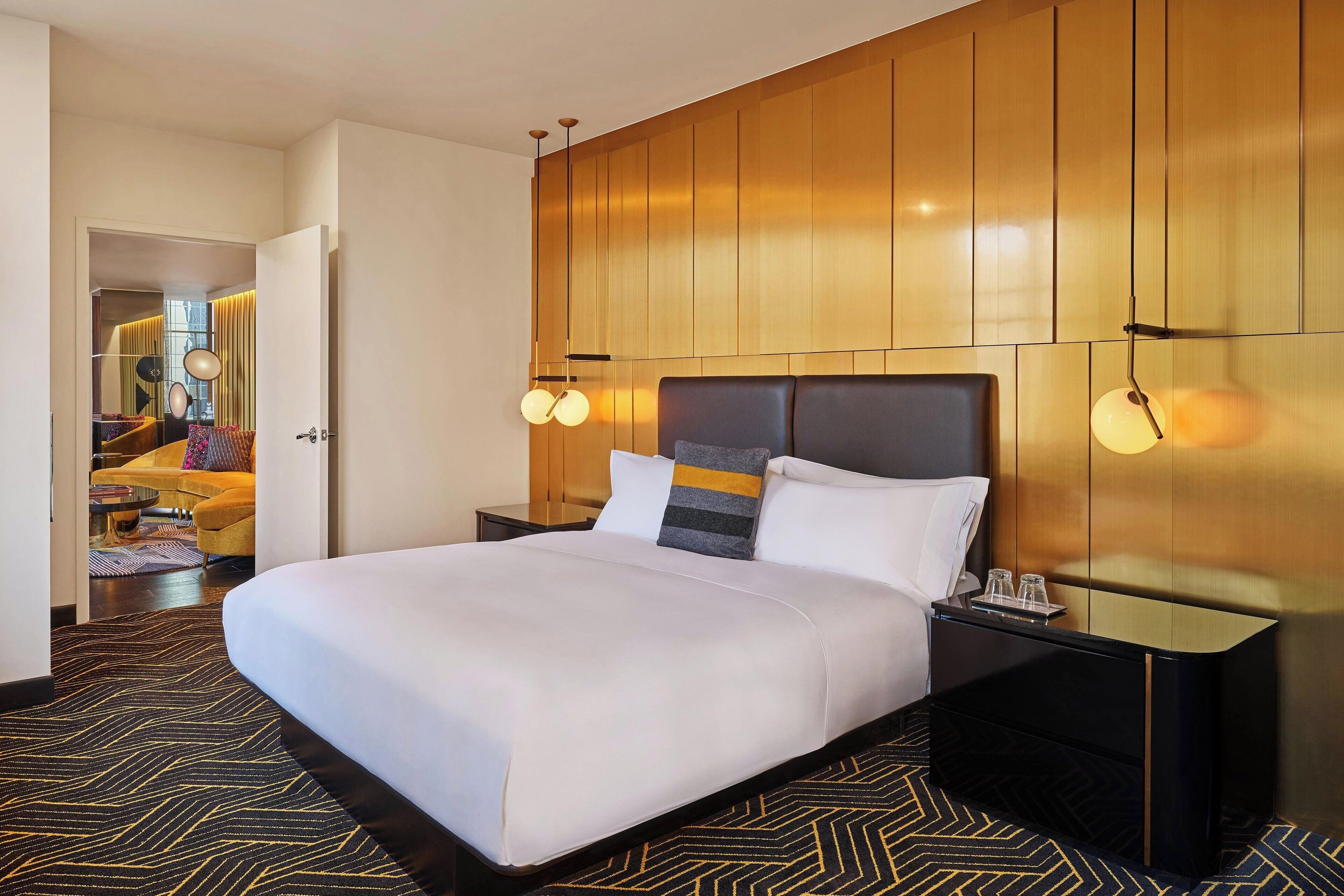 Een hotelkamer met een groot bed, een nachtkastje en een wandlamp.