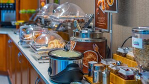 Montaje de bufé con diferentes alimentos y recipientes, incluyendo una olla grande de sopa y varios platos cubiertos.