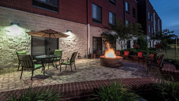 Un patio exterior con un hogar a leña de ladrillo, asientos y una mesa con sillas.