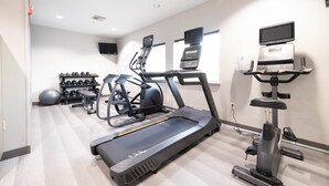Une salle de sport équipée de tapis de course, de vélos elliptiques et de matériel de musculation.