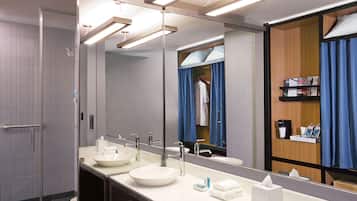 A modern bathroom with two sinks, a large mirror, and a shower area.
