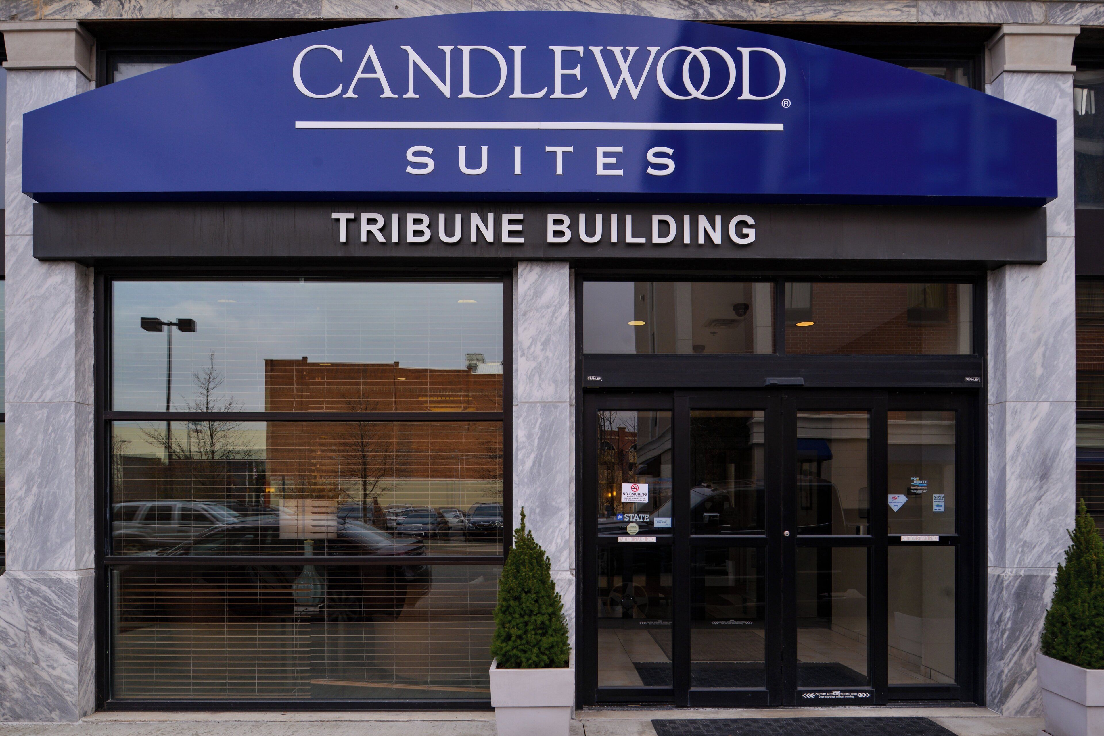 A hotel entrance with a sign reading 'CANDLEWOOD SUITES TRIBUNE BUILDING'.