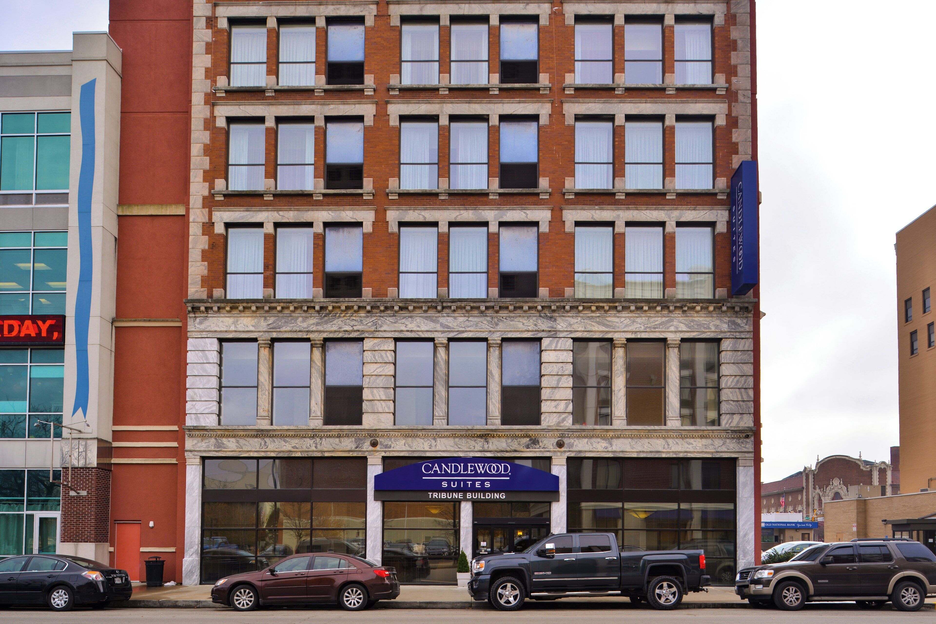 A multi-story building with a 'CANDLEWOOD SUITES' sign, featuring a brick facade and large windows.